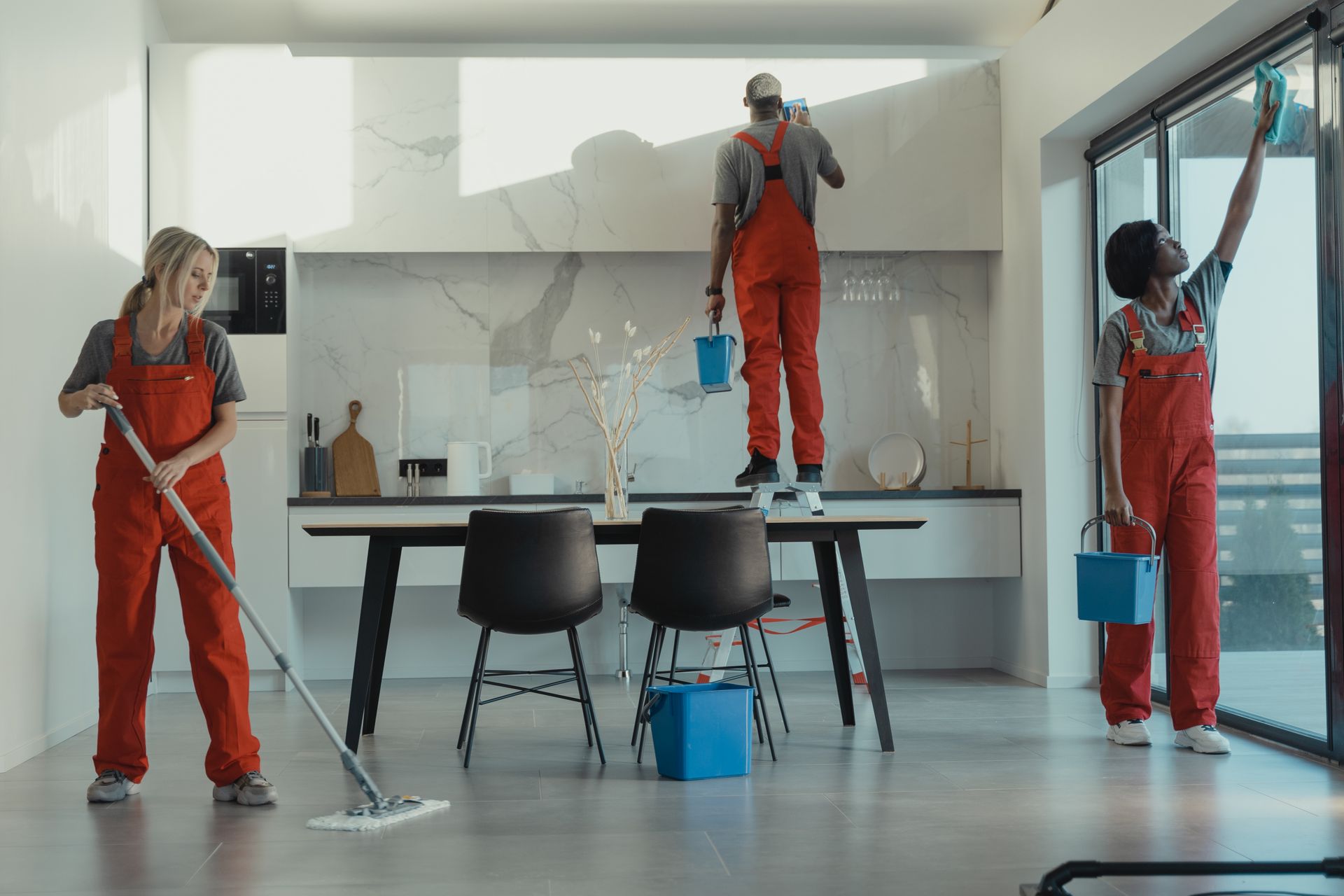 A cleaning team mopping, wiping windows and cleaning a kitchen